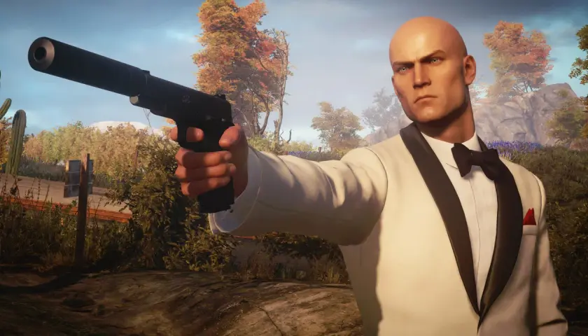 Agent 47 w białym smokingu z pistoletem, gotowy do akcji. Spolszczenie Hitman 3 sprawia, że misje są jeszcze bardziej wciągające.